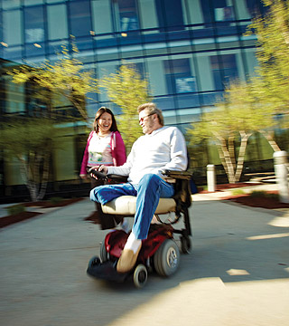 Student in wheelchair in quad area with another student.