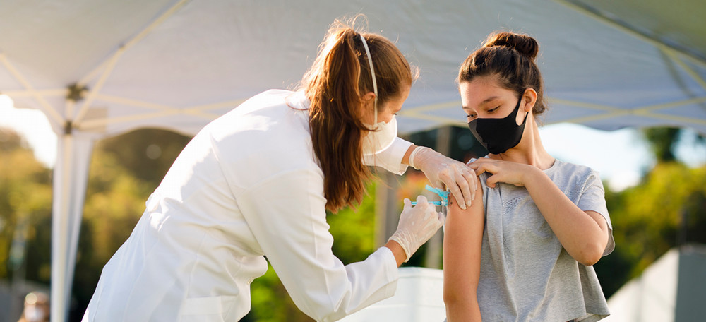 Student getting vaccine shot from a medical professional