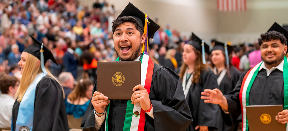 Student graduating and holding up diploma