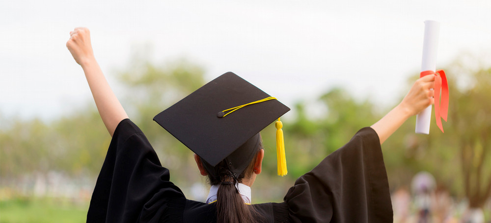 Graduate with arms raised to sky