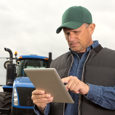 man holding tablet in front of farm equipment