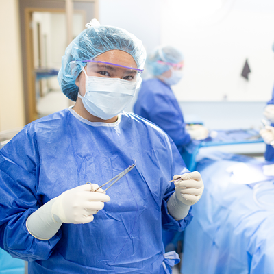 Surgical technologist wearing scrubs and holding surgical equipment