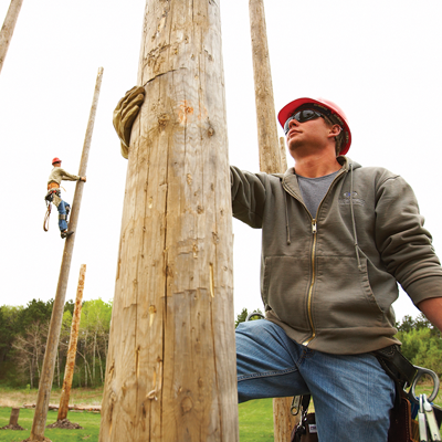 Telecommunications line worker getting ready to climb a utility pole