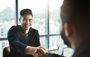 two men shaking hands across a desk