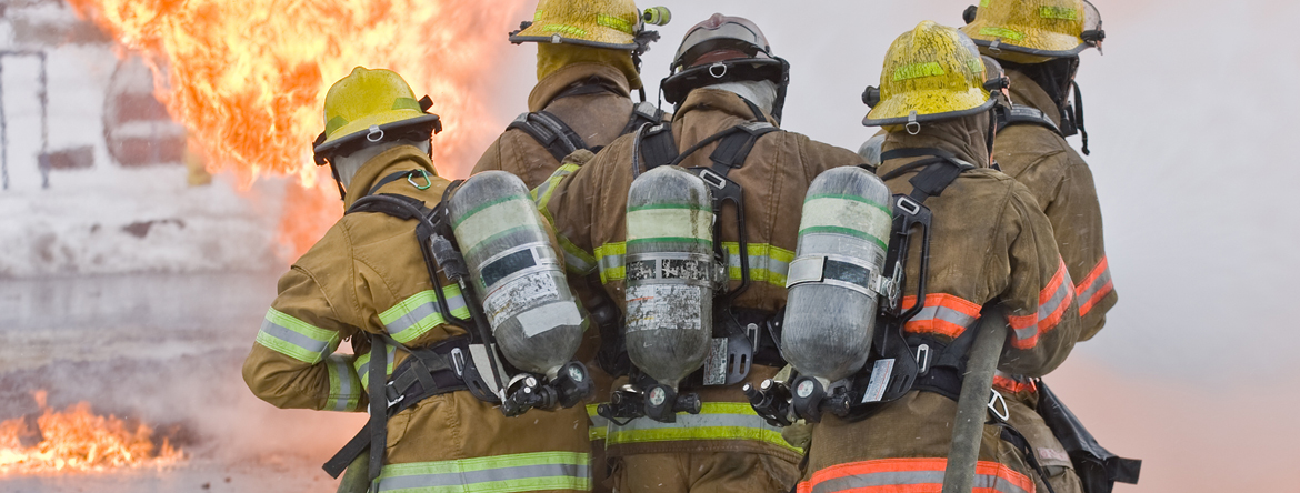 Group of firefighters with hoses in front of fire