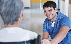 male health care worker talking to a patient in a wheel chair