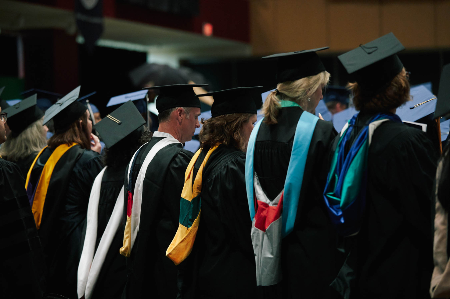 Faculty members standing with students at graduation ceremony