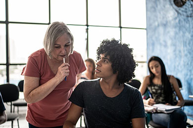 Grey haired instructor mentoring high school boy in dark tshirt