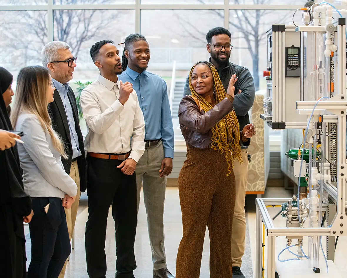 A group of cybersecurity students are discussing industrial control demo lab equipment.